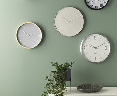 Multiple style clocks on green wall
