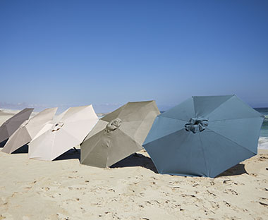 AGGER Market parasol 5 colours displayed on a beach