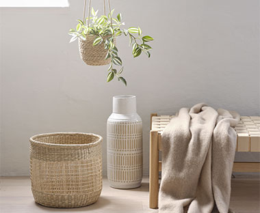 Green artificial plant with a seagrass basket and a white stoneware vase