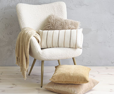 Soft white chair with Nordic-toned pillows and blanket.