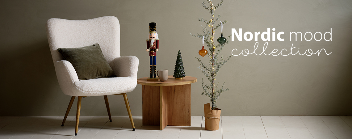 Armchair with a cushion, coffee table with Christmas figurine and a slim Christmas tree decorated with glass baubles