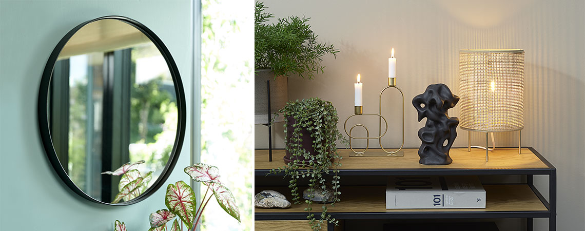 Round mirror on green wall and small table lamp and candlestick