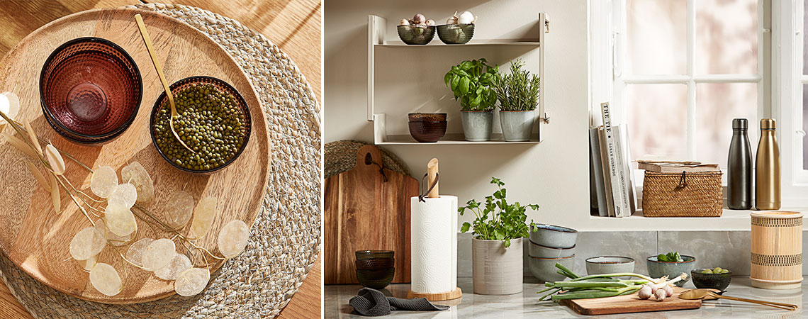 Glass bowls on a wicker placemat and stoneware mugs with fresh herbs on a wall shelf in a kitchen 