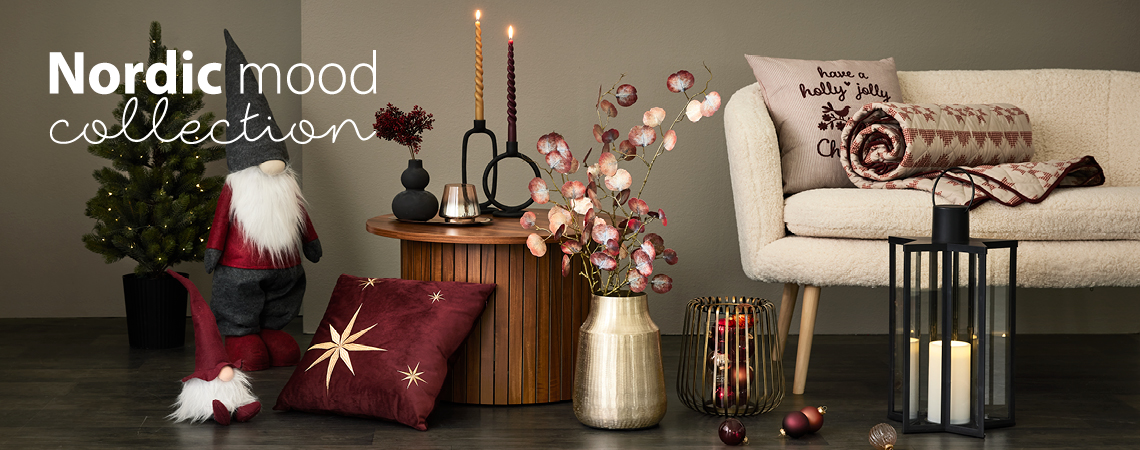 Christmas elves, cushions, golden vase with artificial flower, golden candlestick, and black lantern in front of a white sofa