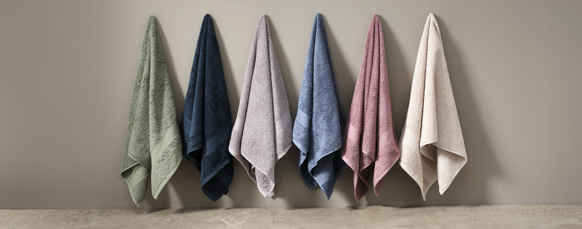 High-quality bath towels in different colours hanging on wall