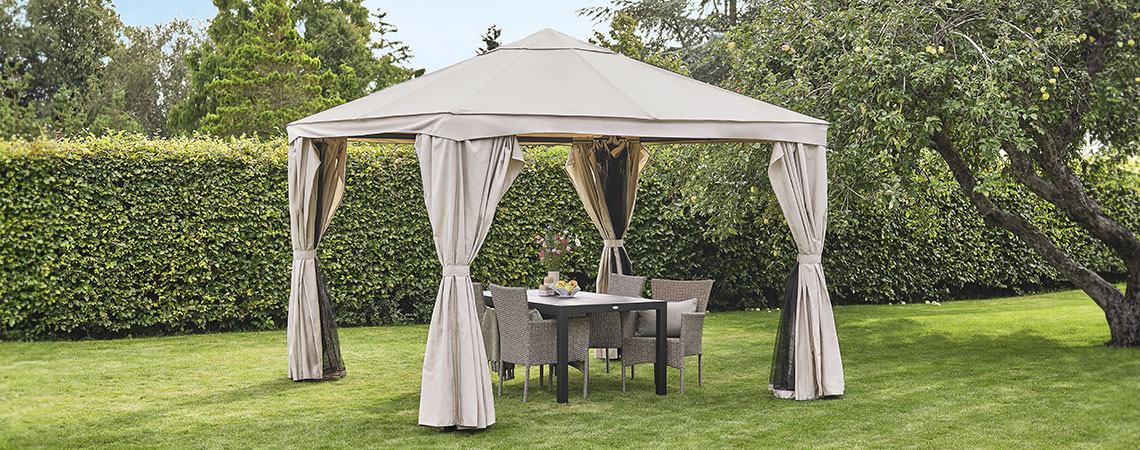 Beige gazebo in a garden with lounge furniture