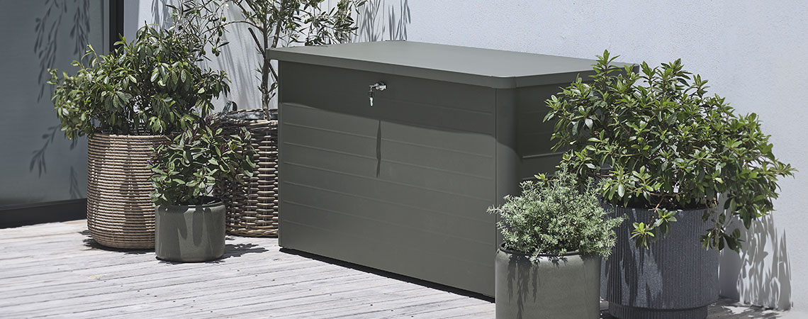 Grey garden cushion storage box on a patio with planters