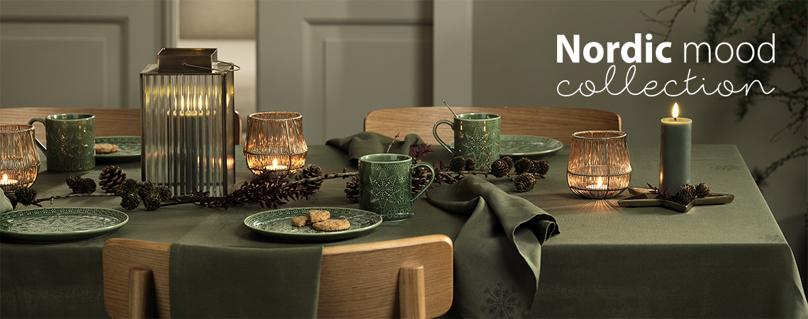 Table set with green Christmas plates, green Christmas mugs, lantern and tealight holders and candles 
