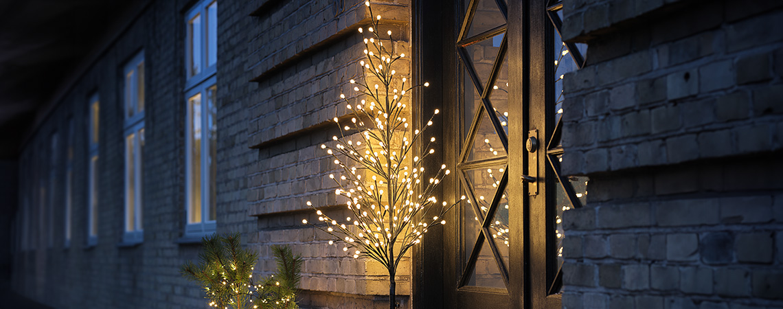 Outdoor Christmas lights such as an LED light tree by the front door of a house 