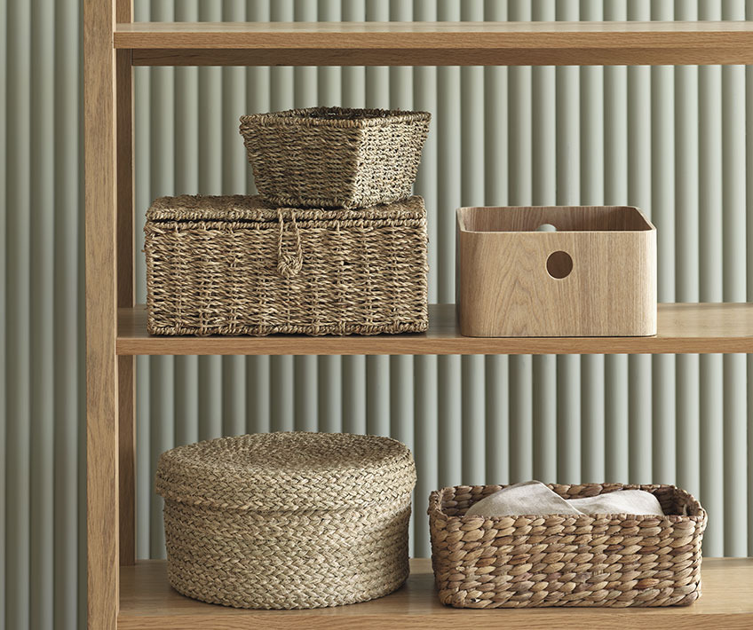 Different baskets and small storage box with lid in a bookcase 
