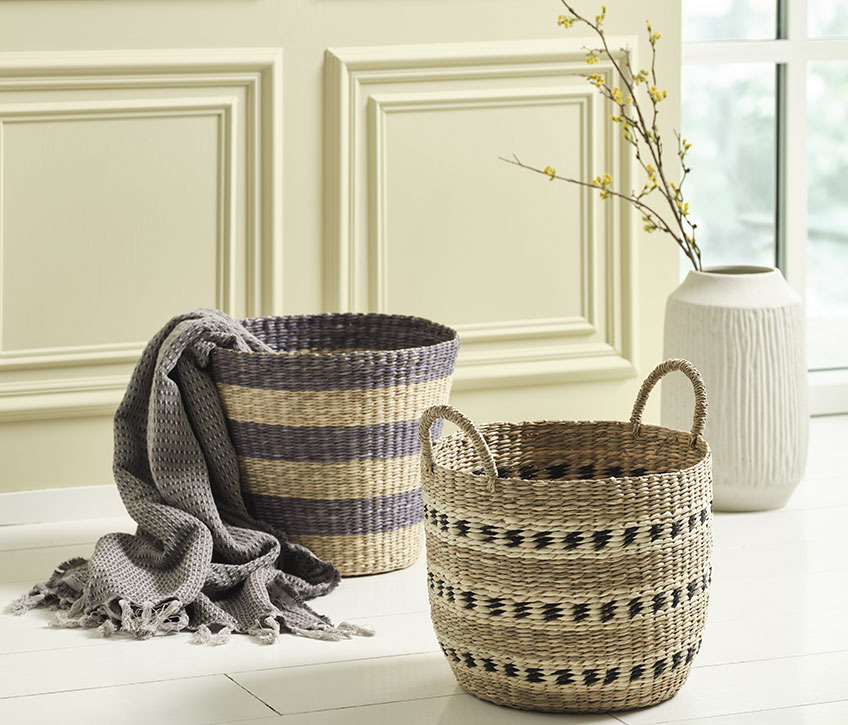 Seagrass baskets on the floor next to a vase 
