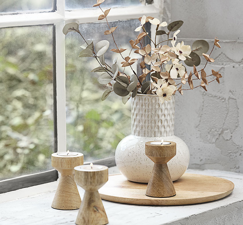 Light beige or white embossed vase with artificial flowers and wooden tealight holders 