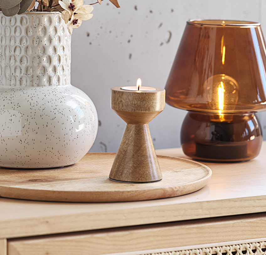 Mango wood tealight holder with white vase and brown glass lamp on wooden sideboard