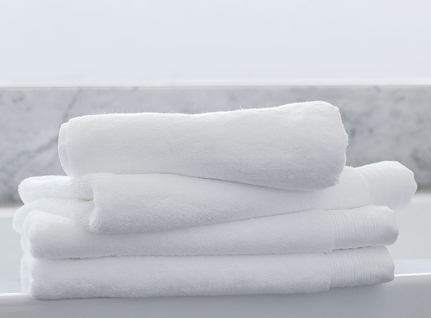 SORUNDA towels are available in white, natural and grey White towels in a stack in a bathroom