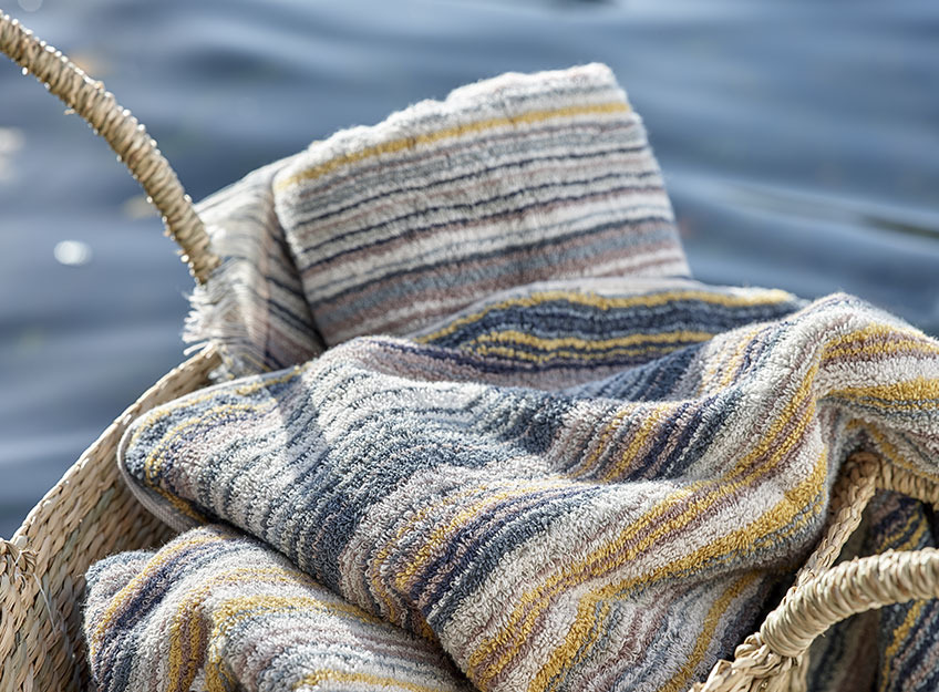 Striped towels in a basket by a lake