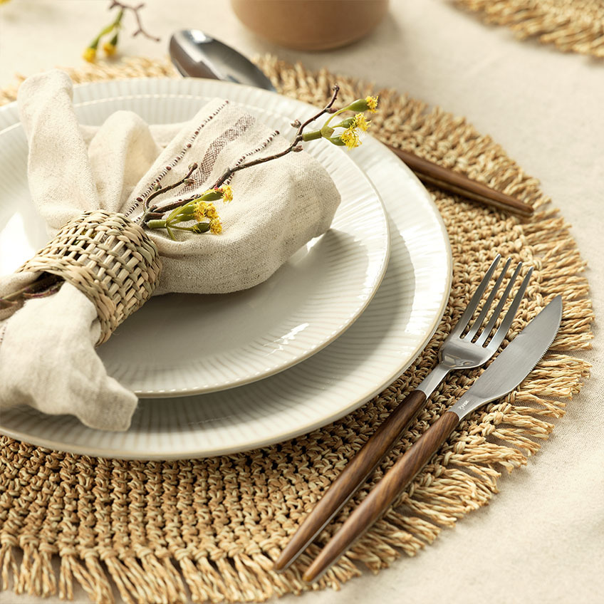 Tableware: White fluted dinner plate, cloth napkin, napkin ring, cutlery set, and placemat 