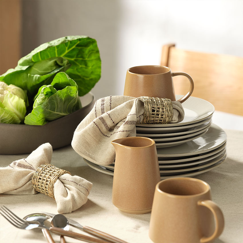Tableware: Mug, milk jug, cloth napkins with napkin rings, and salad bowl on dining table
