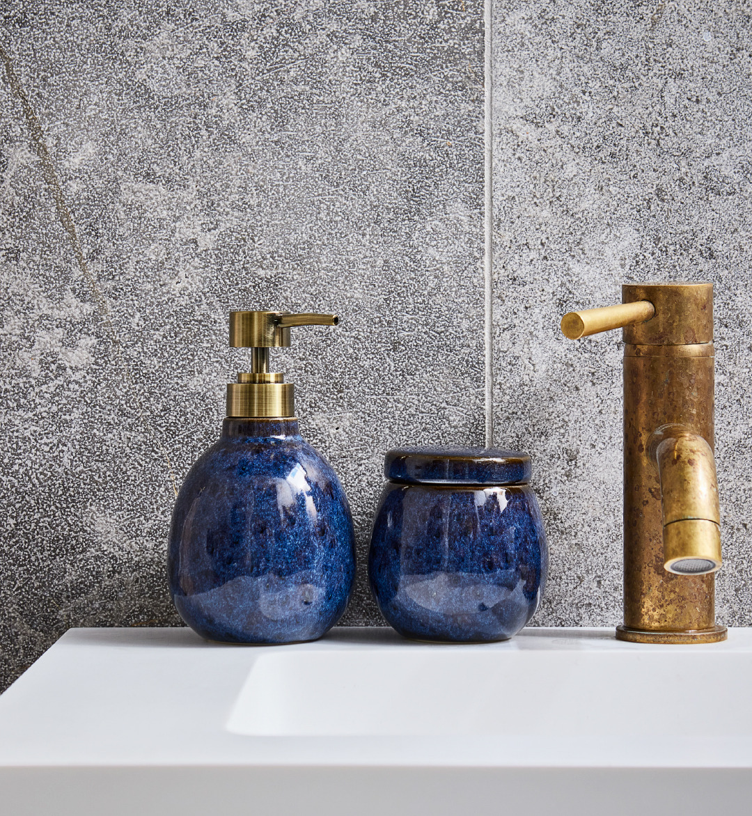 Blue bathroom soap dispenser and storage jar on sink