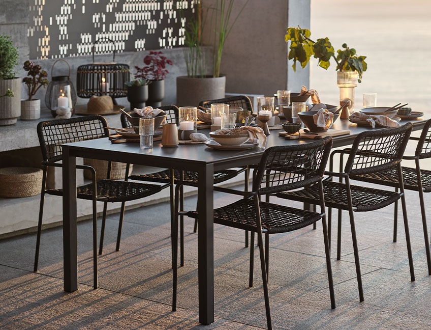 Garden table and garden chairs with table set for dinner on patio by sunset