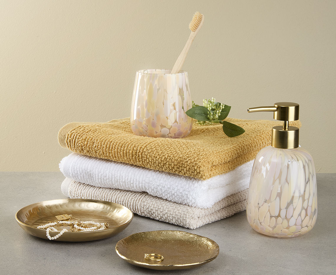 Stack of towels with toothbrush holder, soap dispenser and trinket dishes
