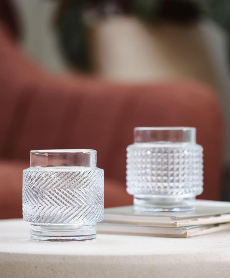 A pair of glass tealight holders on an end table