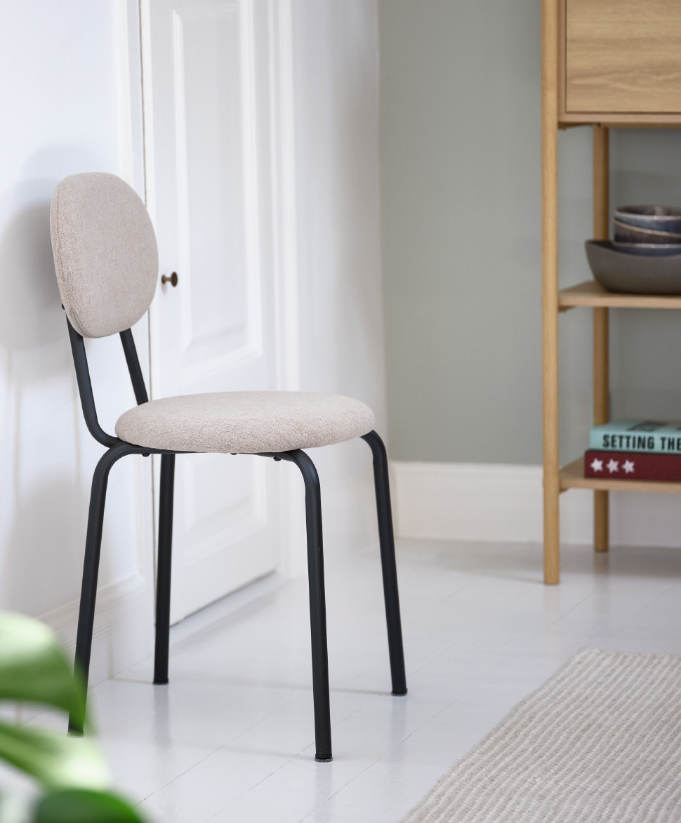 Sand fabric dining chair leaning against a wall