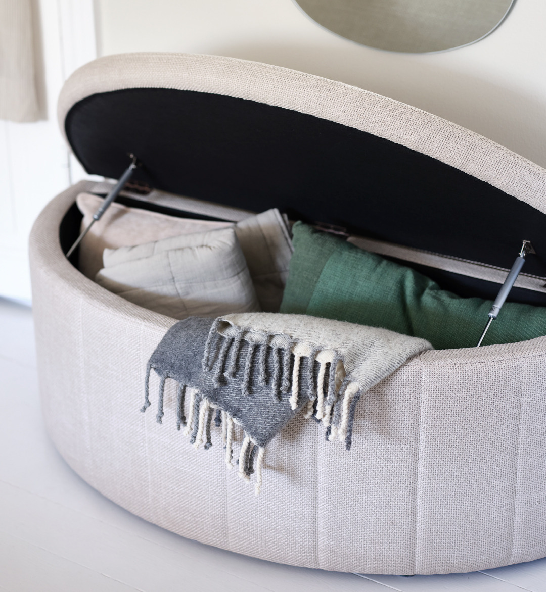 Storage bench open displaying multiple earth tone throws and cushions