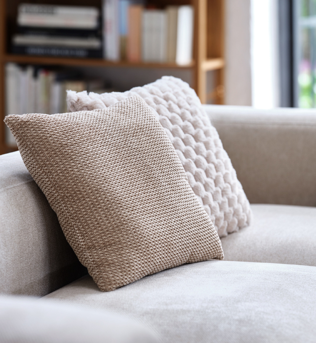 Two beige decorative cushions on a sand coloured sofa