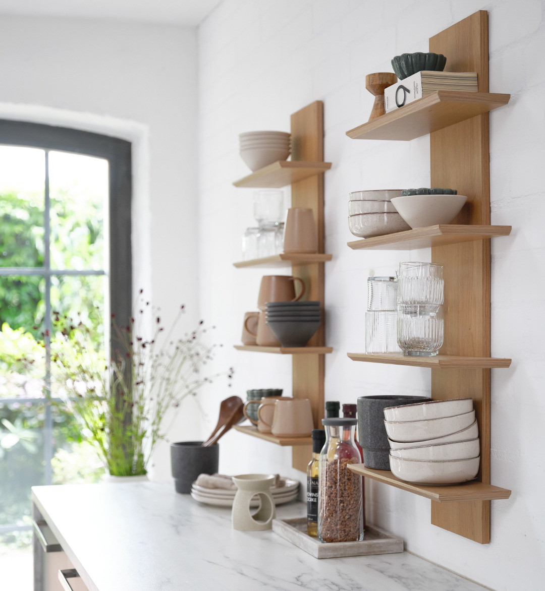 Two oak coloured wall shelves with ceramic and glass kitchenware 