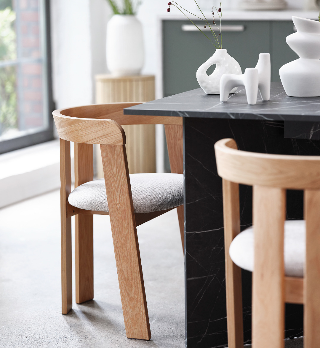 black marble dining table and two beige and oak dining chairs with white candlestick holder and two vases