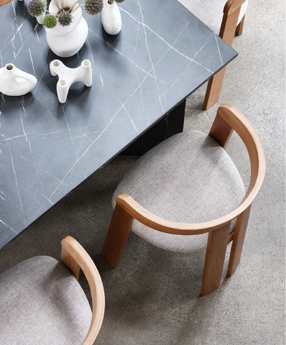 Overview shot of a black marble dining table and five beige and oak dining chairs