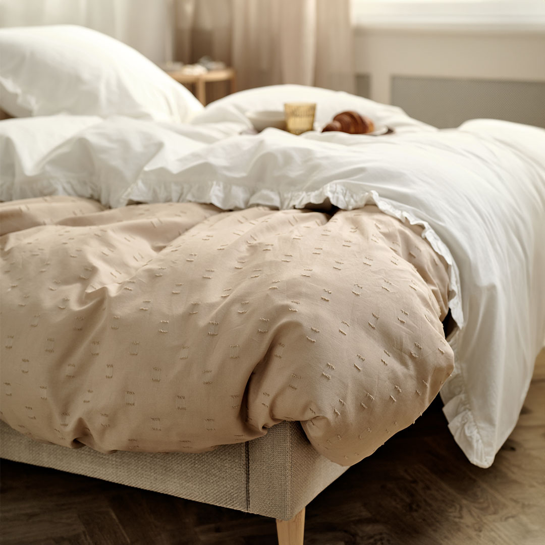 Sand coloured duvet cover and white linen in a bedroom