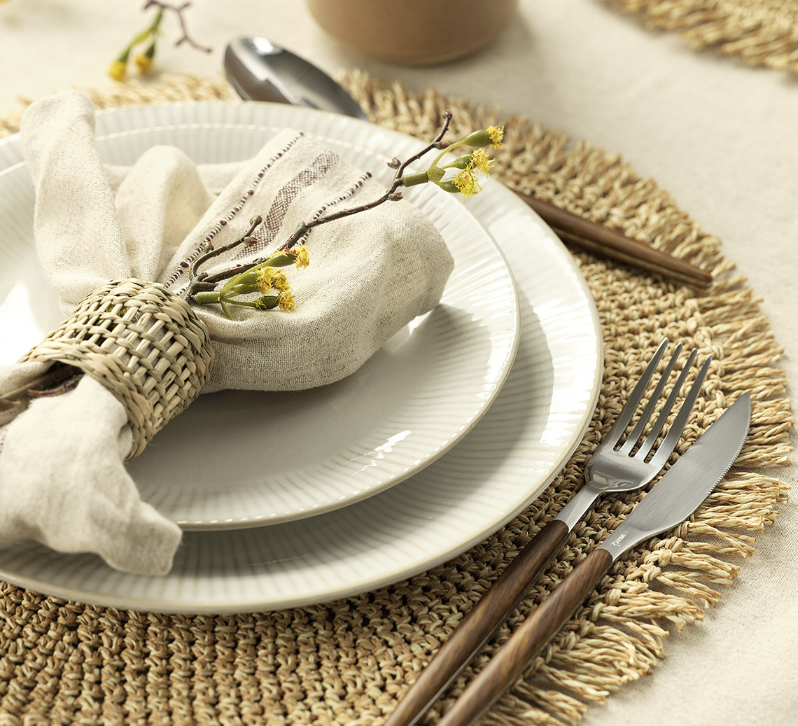 Place setting with a round place mat, plates, napkin and cutlery  