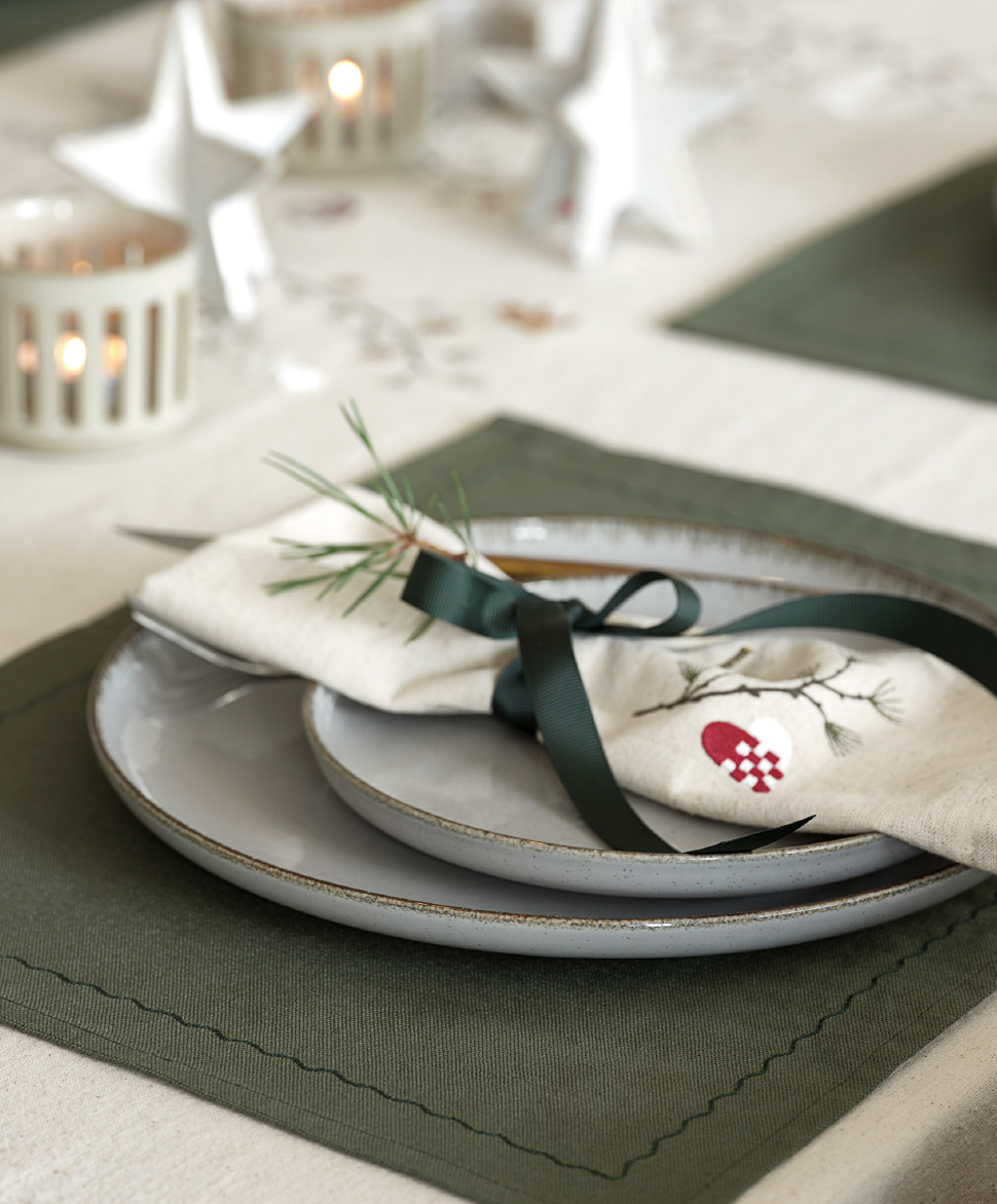 Decorative white cloth napkins atop a dinner plate and green place mat