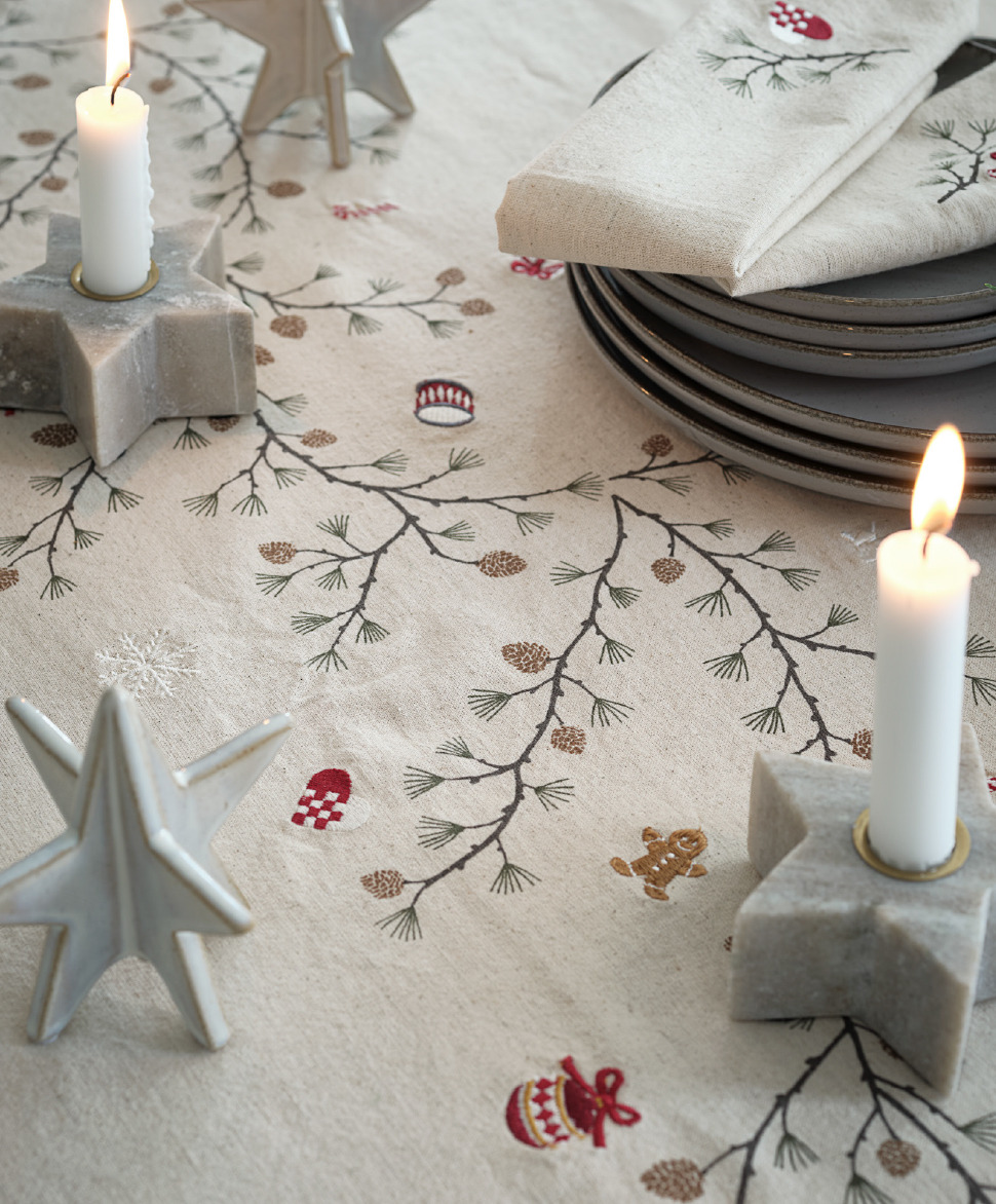 Star Christmas decoration next to two star candle holders on top of a Christmas table cloth