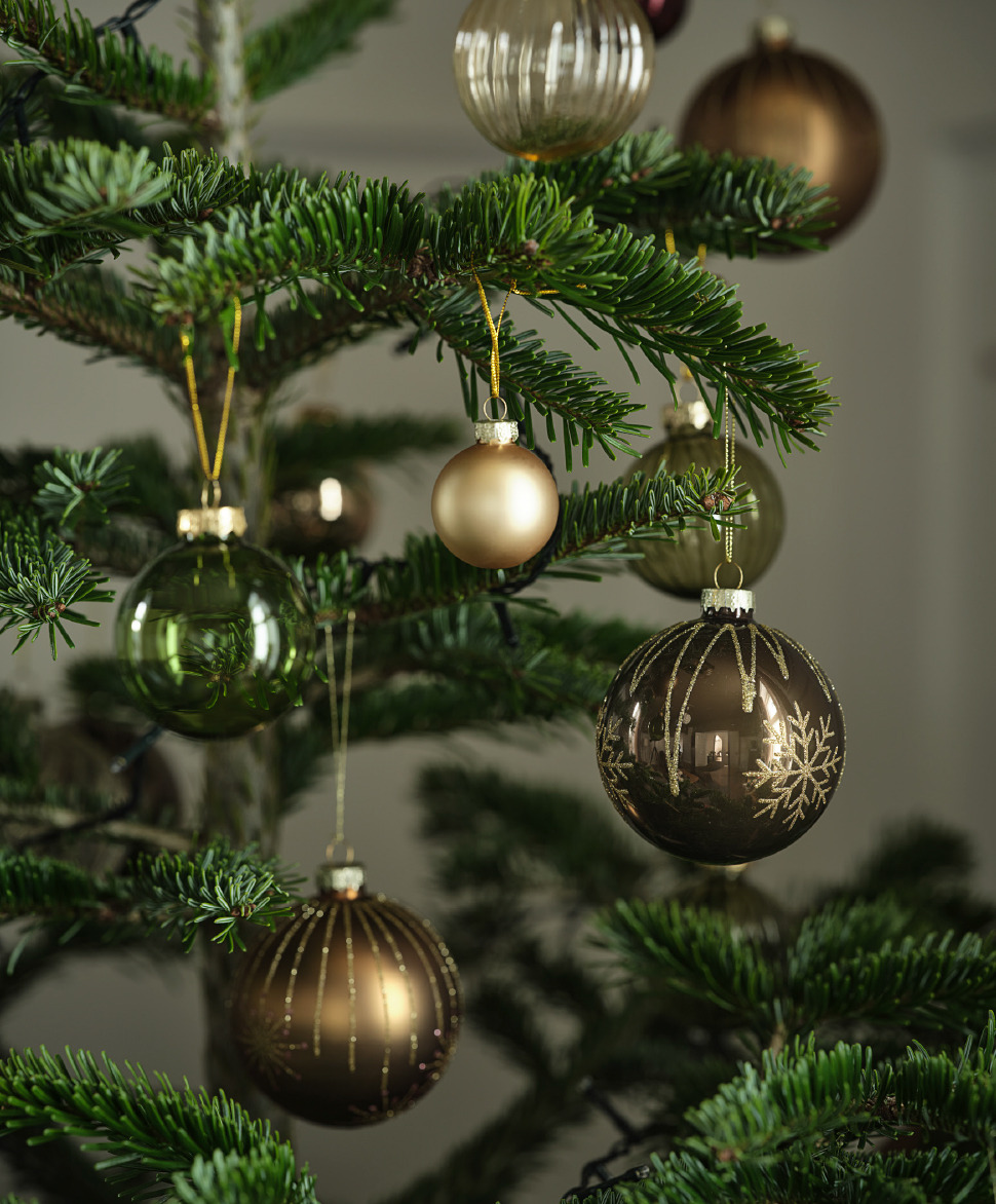 Gold and green Christmas baubles hanging from a tree