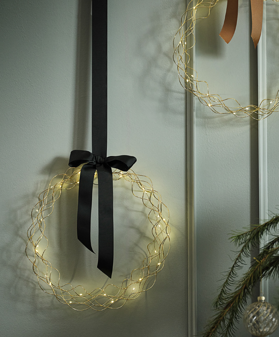 LED Christmas wreaths with bows hanging on a green wall