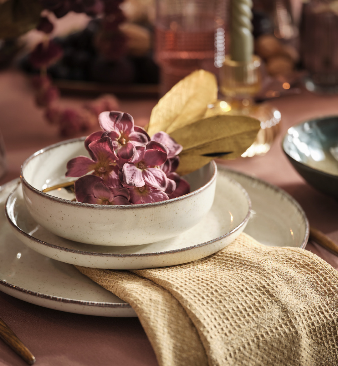 Stoneware beige bowl and plates on top of a decorated tablescape