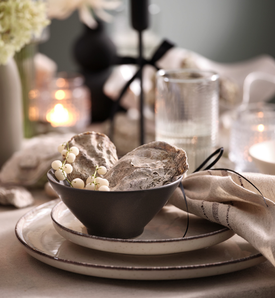 Dark grey bowl sitting on plates and a natural coloured cloth napkin