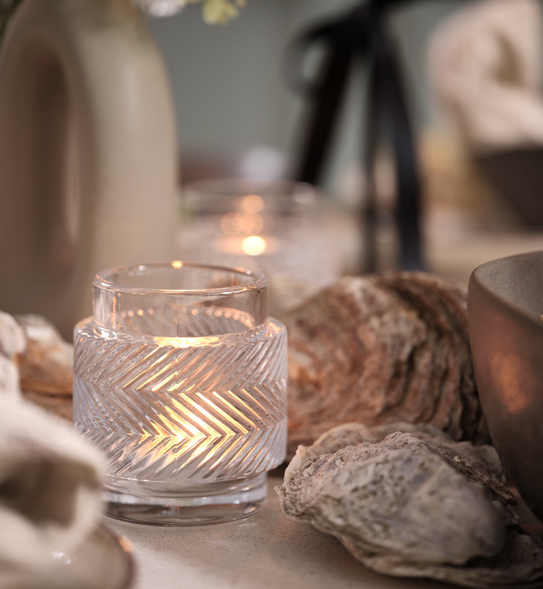 Clear glass tealight holders next to oyster shells on a table