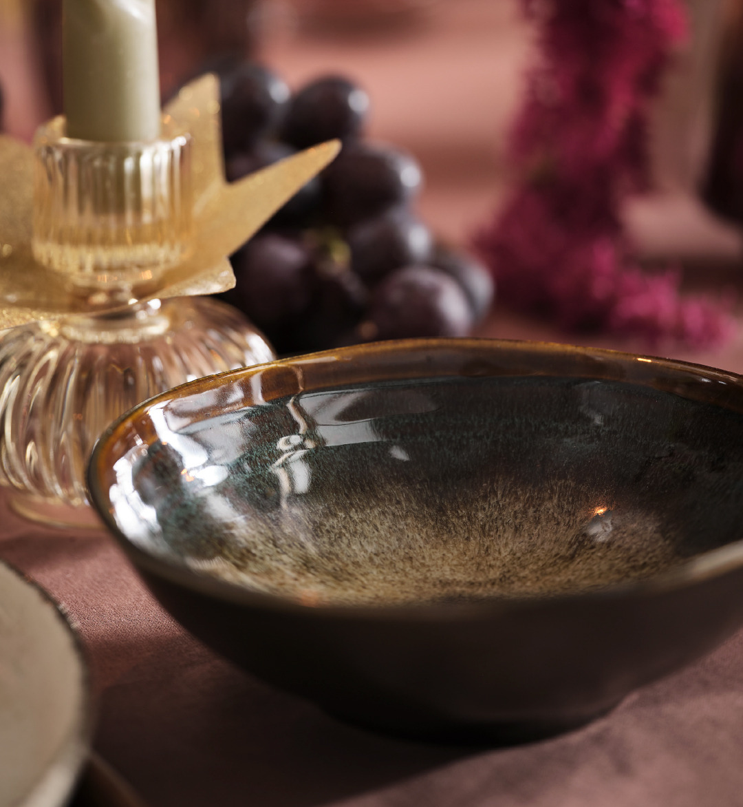 Dark multicolored bowl and candle stick holder on a tablescape