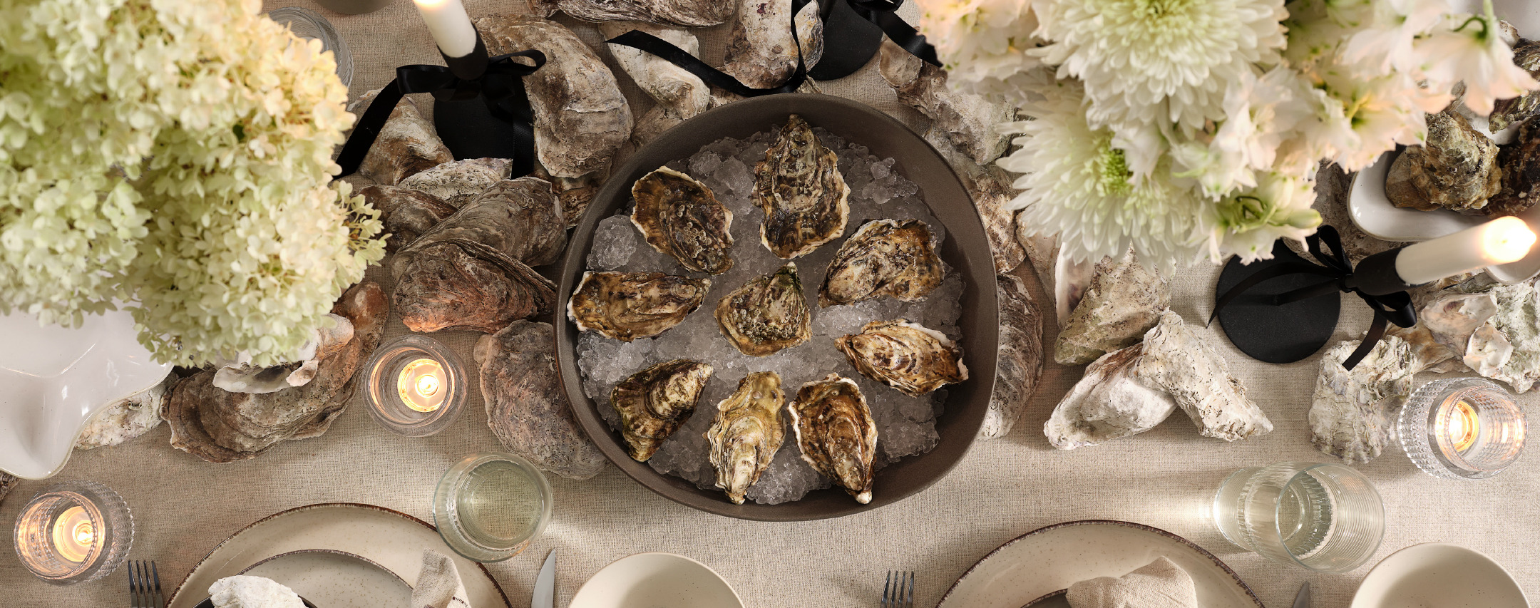 Large bowl with oysters at the center of a tablescape with white and light green flowers