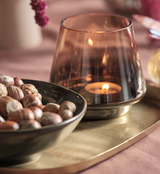 Glass tealight holder on gold tray on top of a dinner table