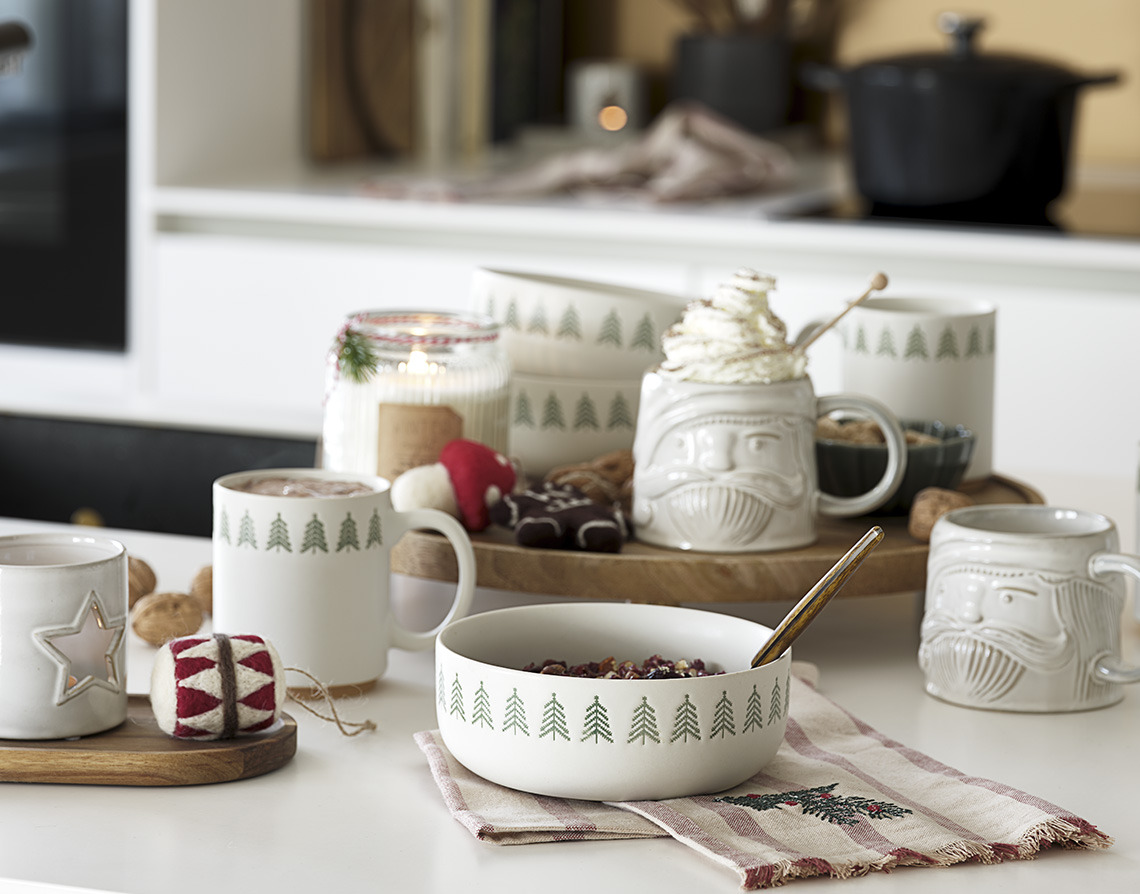 Christmas mugs, bowls and candles on a table 