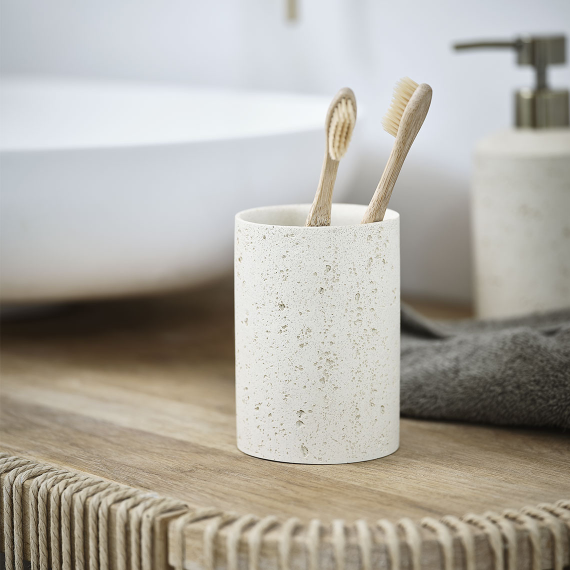 Toothbrush holder in beige stoneware standing on a bathroom sink