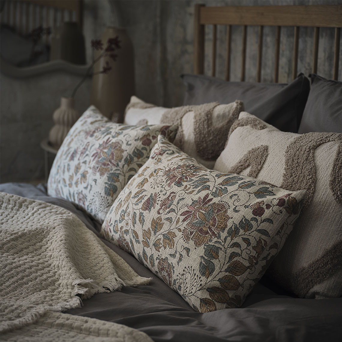 Floral printed and beige cushions in a bed with a beige throw