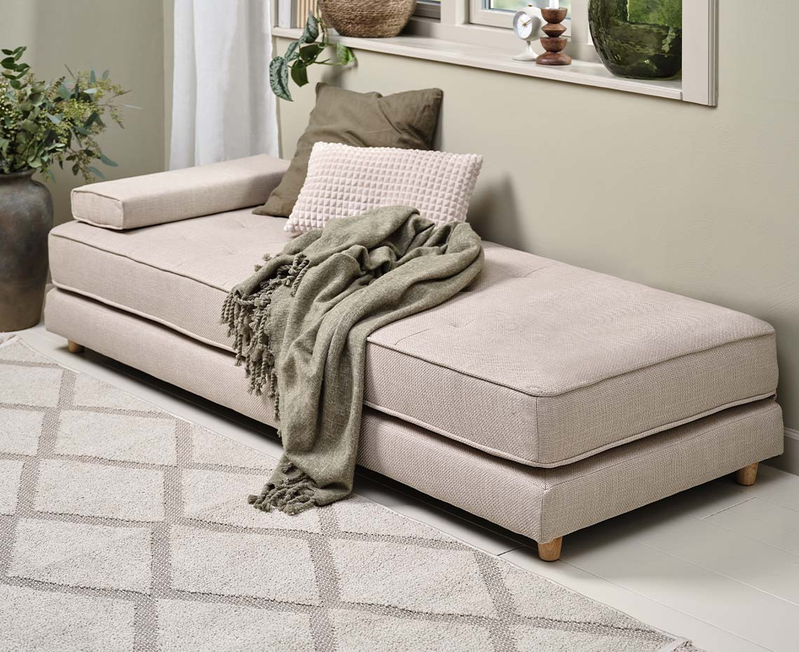 Beige daybed in living room with cushions and throw