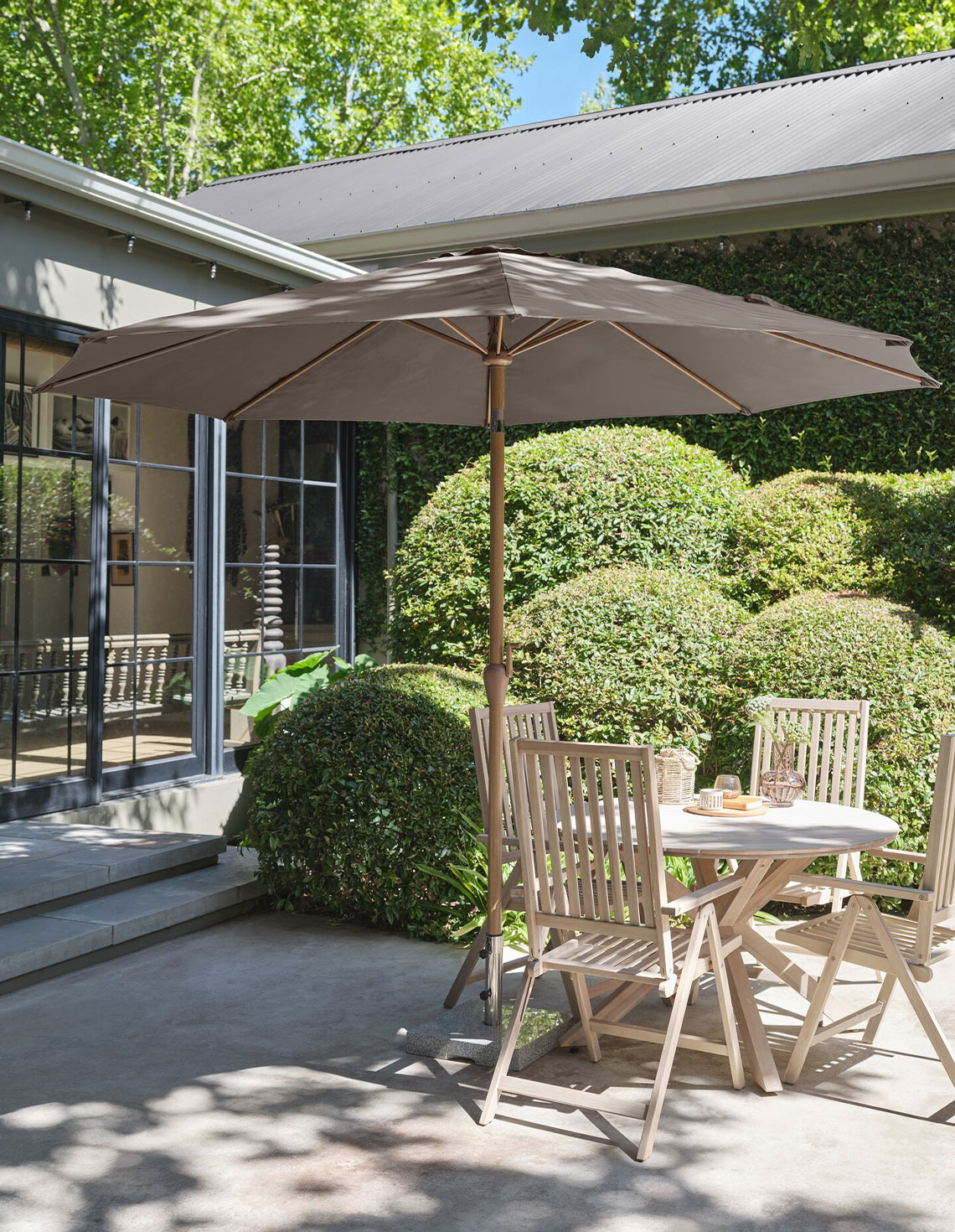 Large beige parasol on patio with garden table and garden chairs