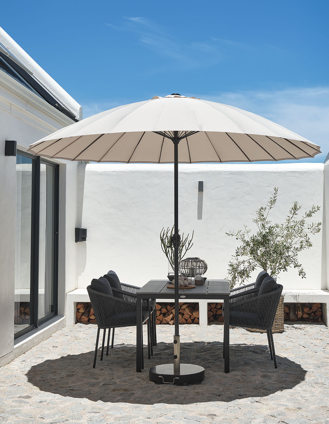 Classic beige garden parasol on patio with garden table and garden chairs