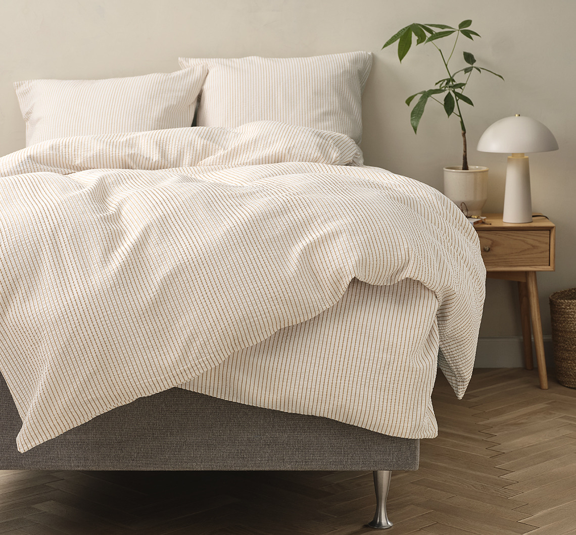 Striped bed linen in a light bedroom